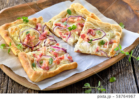 Tarte Flambee from Alsace with onions and bacon, similar to a pizza, thin dough with sour cream Tarte Flambee from Alsace with onions and bacon, similar to a pizza, thin dough with sour cream 58764967