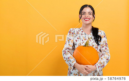 Young woman holding a pumpkin 58764976