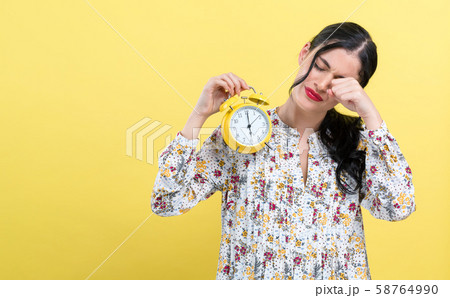 Yong woman holding a clock showing 6AM 58764990