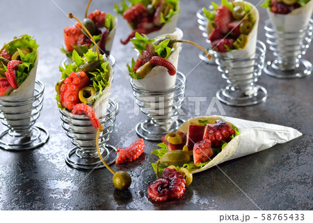 Mini tortillas stuffed with octopus salad with olives and capers, served in wire egg cups Mini tortillas stuffed with octopus salad with olives and capers, served in wire egg cups 58765433