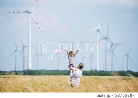 Mature father with small daughter standing on field on wind farm. Mature father with small daughter standing on field on wind farm. 58765587