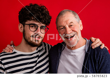 Young man and senior father in a studio on red background. 58765823