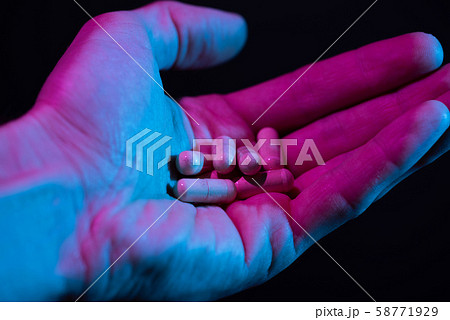Heap of pills in hand closeup on dark background. Drugs tablets pile in palm. 58771929