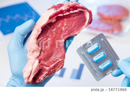 Fresh red meat steak and drugs pills in laboratory scientist hands. Livestock meat antibiotic and hormone use concept. 58771966