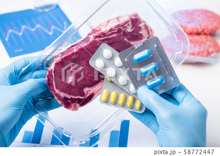 Packaged meat and pills in lab scientist hands. Livestock antibiotic use concept. 58772447