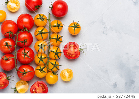 Tomatoes. Cherry tomato assortment, fresh red ripe on branch, red and yellow, whole and cut in half, on rustic table flat lay with copy space. 58772448