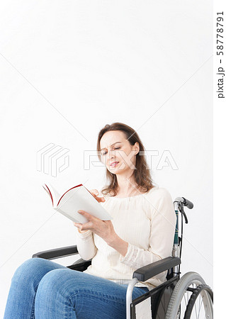 車椅子に乗り読書をする外国人の女性 58778791