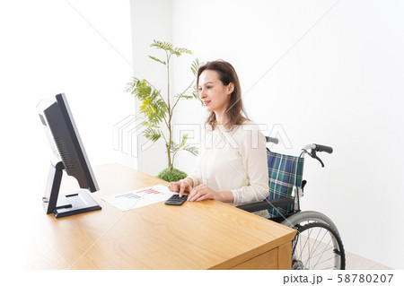 車椅子でデスクワークをする外国人の女性 車椅子でデスクワークをする外国人の女性 58780207