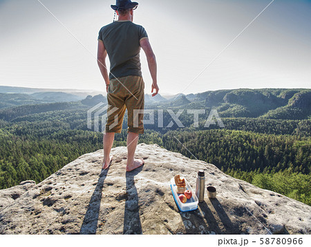 Man with lunch box on cliff at sunset time, sun 58780966