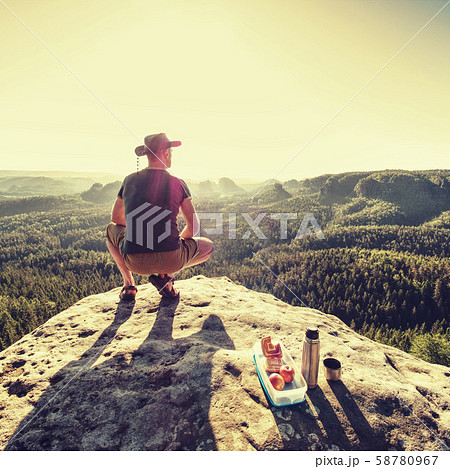 Young man relaxing on rocky cliff. Man sitting on Young man relaxing on rocky cliff. Man sitting on 58780967