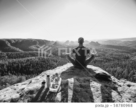 Young man relaxing on rocky cliff. Man sitting on Young man relaxing on rocky cliff. Man sitting on 58780968