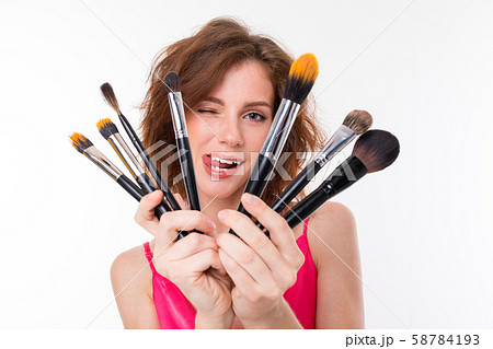 beautiful girl on a white background fooling around with makeup brushes, photographer on a white beautiful girl on a white background fooling around with makeup brushes, photographer on a white 58784193