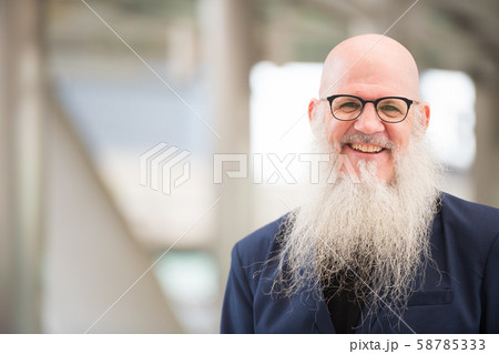 Face of happy mature bearded bald businessman smiling in the city outdoors Face of happy mature bearded bald businessman smiling in the city outdoors 58785333