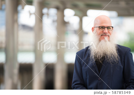 Mature bearded bald businessman with eyeglasses thinking in the city outdoors 58785349