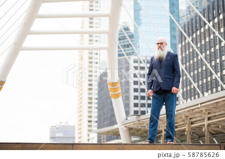 Full body shot of mature bearded bald businessman in the city outdoors Full body shot of mature bearded bald businessman in the city outdoors 58785626