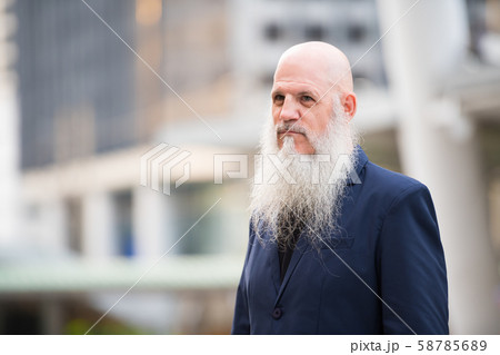 Mature bearded bald businessman thinking in the city outdoors Mature bearded bald businessman thinking in the city outdoors 58785689