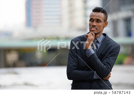 Happy young African businessman thinking in the city streets outdoors 58787143