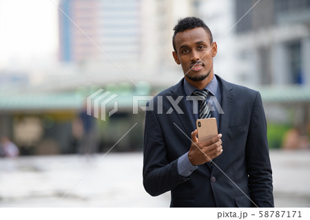 Happy young African businessman using phone in the city Happy young African businessman using phone in the city 58787171