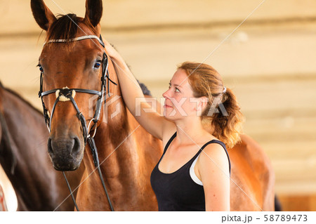 Jockey young girl petting and hugging brown horse Jockey young girl petting and hugging brown horse 58789473