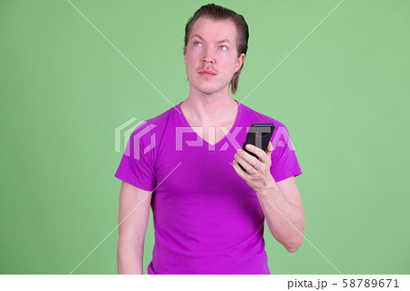 Portrait of young handsome man thinking while using phone Portrait of young handsome man thinking while using phone 58789671