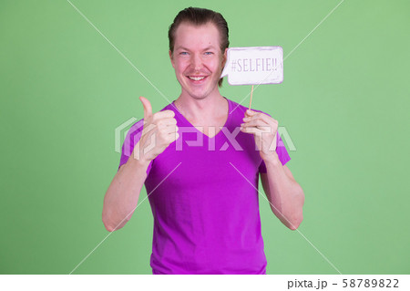Portrait of happy young man with selfie paper sign giving thumbs up Portrait of happy young man with selfie paper sign giving thumbs up 58789822