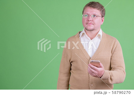 Portrait of overweight bearded man thinking while using phone Portrait of overweight bearded man thinking while using phone 58790270