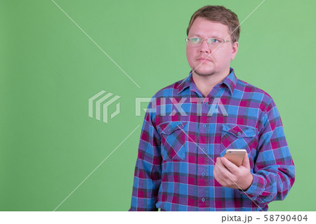 Overweight bearded hipster man thinking while using phone 58790404