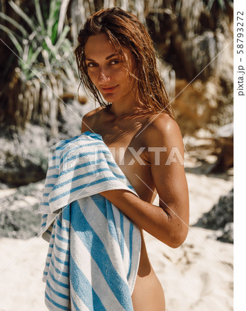 Attractive naked woman with towel at tropical beach. 58793272