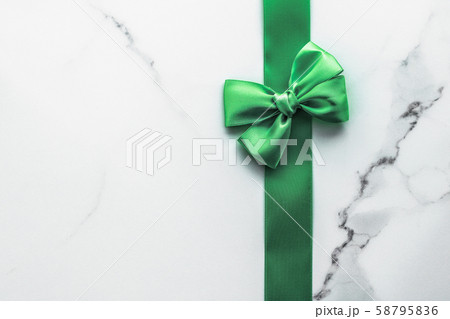 Green silk ribbon and bow on marble background, St Green silk ribbon and bow on marble background, St 58795836
