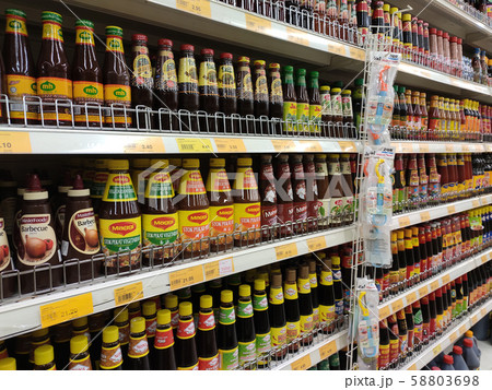 Selective focused variety of cooking sauce in the bottles displayed for sale in the supermarkets. Displayed on racks and separated by the brand to facilitate buyers. 58803698