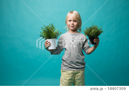 A little boy holding pots with a green plant. Children and nature. Preserve nature A little boy holding pots with a green plant. Children and nature. Preserve nature 58807309