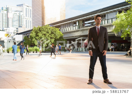 Portrait of young handsome businessman wearing suit in city 58813767