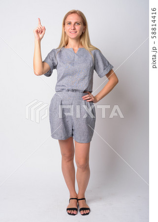 Full body shot of happy young blonde woman pointing up Full body shot of happy young blonde woman pointing up 58814416