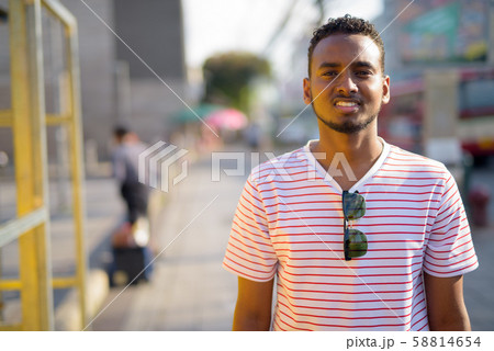 Happy young African bearded man with Afro hair in the streets 58814654