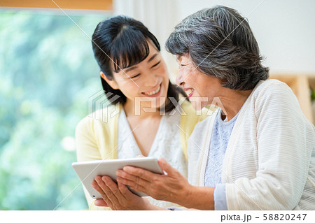 タブレット端末を操作する親子　母子　シニア女性　ミドル女性　2人 58820247