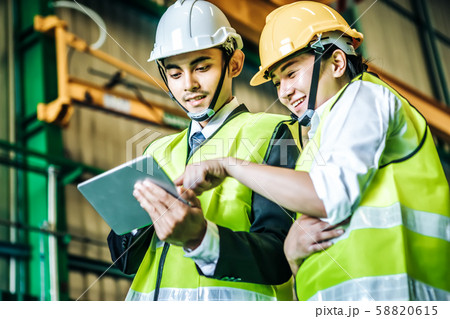 Asian engineer man wearing white helmet with his Asian engineer man wearing white helmet with his 58820615