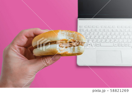 デスクまたはテーブルでハンバーガーを食べる人 デスクまたはテーブルでハンバーガーを食べる人 58821269