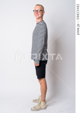 Full body shot profile view of happy young blonde man looking at camera 58823482