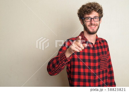 Happy young bearded hipster man with curly hair pointing at camera Happy young bearded hipster man with curly hair pointing at camera 58823821