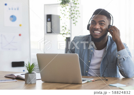 Smiling employee working on laptop and listening music in headphones 58824832