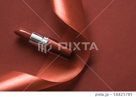 Luxury lipstick and silk ribbon on bronze holiday Luxury lipstick and silk ribbon on bronze holiday 58825785