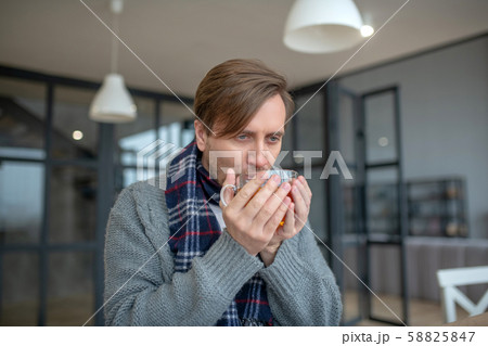 Dark-haired man enjoying hot black tea while having sore throat 58825847
