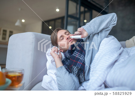 Sick man using nasal spray while having stuffy nose 58825929