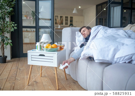 Sick man having napkin in his hand while falling asleep Sick man having napkin in his hand while falling asleep 58825931