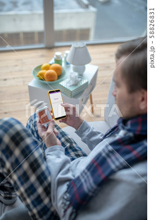 Man holding smartphone while reading about vitamins Man holding smartphone while reading about vitamins 58826831