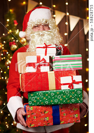 Santa Claus posing with many gifts, sitting indoor 58828755