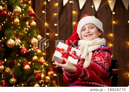 Cheerful santa helper girl with gift box sitting Cheerful santa helper girl with gift box sitting 58828770