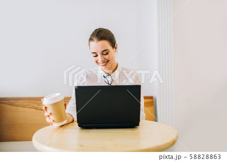 Young girl sitting in a cafe, working on laptop computer. Young girl sitting in a cafe, working on laptop computer. 58828863