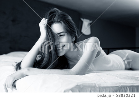 Young redheaded woman half-naked lying on the bed. 58830221