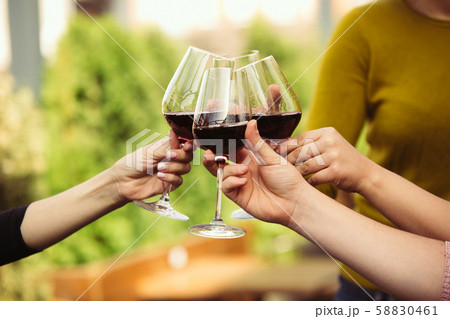 People clinking glasses with wine on the summer terrace of cafe or restaurant. Close up shot 58830461